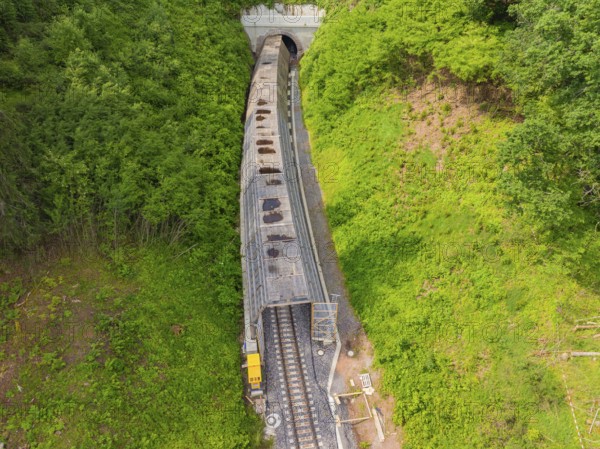 A train emerges from a tunnel, surrounded by green nature, construction of the Hermann Hesse railway, Calw, Germany