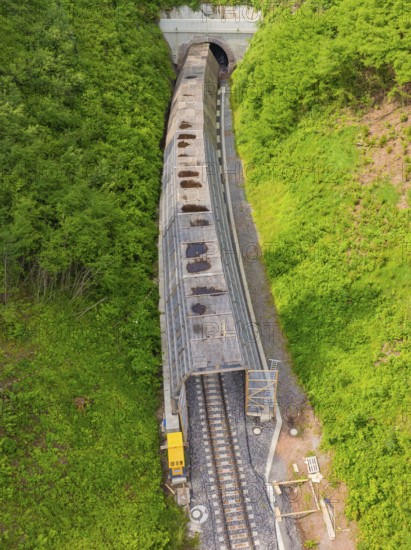 Aerial view of a railway tunnel stretching through green hills and a dense forest, construction of the Hermann Hesse Railway, Calw, Germany