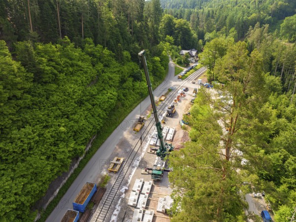 Construction work with a crane along railway tracks, surrounded by forest, construction of the Hermann Hesse railway, Calw, Germany