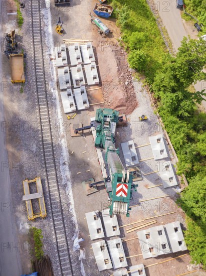 Industrial site with crane, concrete blocks and railway tracks surrounded by trees from an aerial perspective, construction of the Hermann Hesse railway, Calw, Germany
