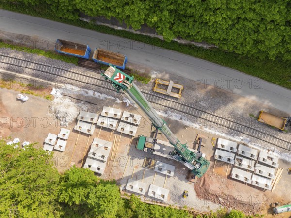 Industrial structure from the air with railway tracks and concrete blocks adjacent to a road, surrounded by forest, construction of the Hermann Hesse railway, Calw, Germany