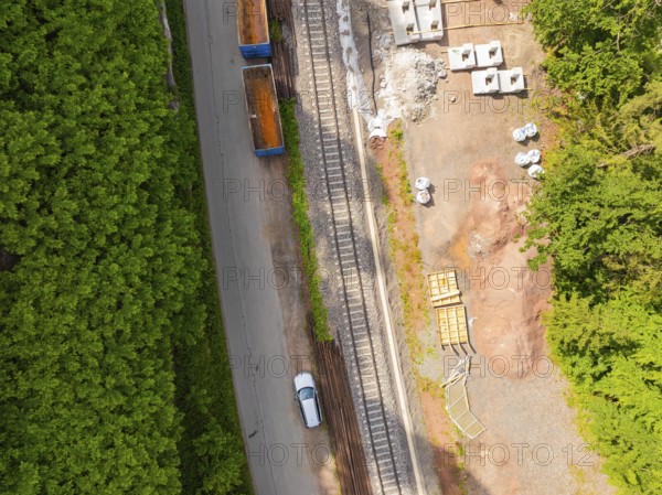 View of street scene with railway tracks and a car through dense forest, construction of the Hermann Hesse railway, Calw, Germany