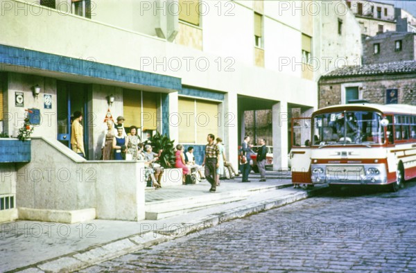 People outside hotel waiting to board tour bus coach, Piazza Armerina, Sicily 1960s