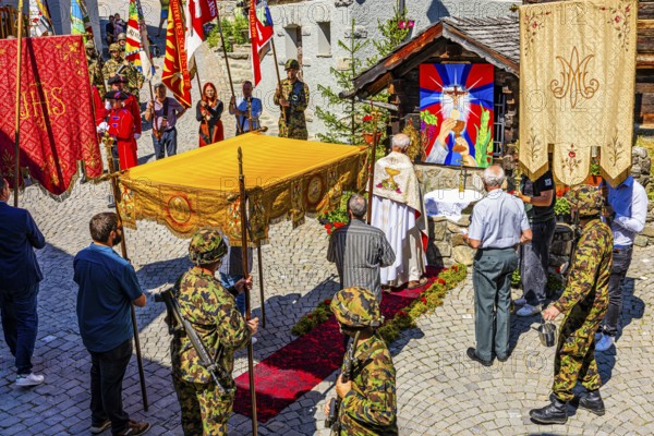 The priest celebrates a service at the flower-decorated altar during the Corpus Christi procession, historic town centre, Grimentz, Val d'Anniviers, Valais Alps, Canton Valais, Switzerland