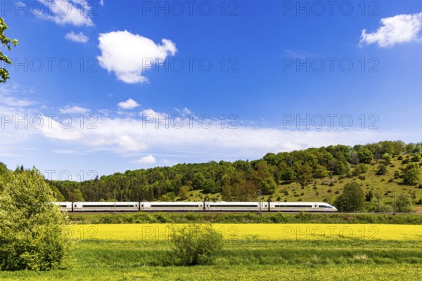 InterCityExpress ICE en route on the Swabian Alb near Lonsee. Landscape on the railway's Filstalline line in spring with rape fields in bloom. Lonsee, Baden-Württemberg, Germany