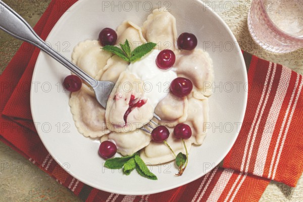 Traditional dumplings with cherries and yogurt, close-up, no people