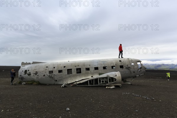 Tourist on aircraft wreckage, US Navy Douglas DC-3 transport plane, Sander, volcanic landscape, Sólheimasandur, Solheimasandur, near ring road, Suðurland, Sudurland, South Iceland, Iceland