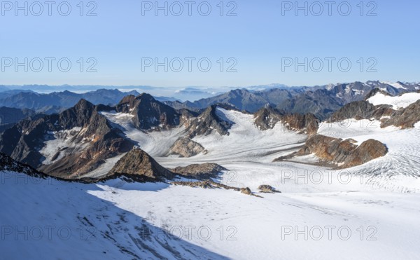 Narrow rocky ridge at the Wilder Freiger summit, picturesque high mountain landscape with snow, view of Übeltalferner glacier and rocky mountain peaks Königshofspitz and Sonklarspitze, Stubai Alps, South Tyrol, Italy