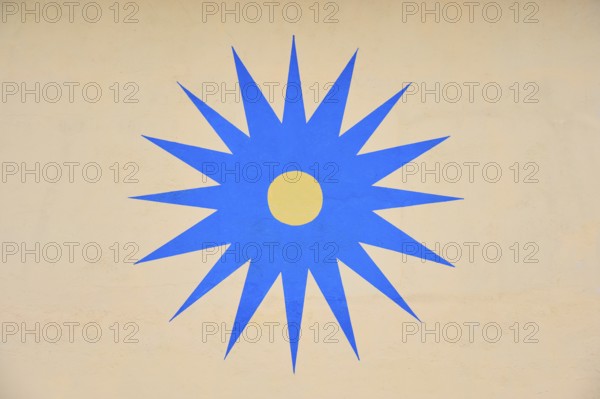 Blue stylised star with yellow centre on beige background, Rüdesheim am Rhein, Rhine Valley, Rheingau-Taunus-Kreis, Hesse, Germany
