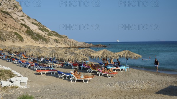 Sandy beach beach with sun loungers and parasols, surrounded by rocky hills, Agios Stefanos Beach, Agios Stefanos Basilica, Agios Nikolaos Chapel, Kastri Island, Kos, Dodecanese, Greek Islands, Greece