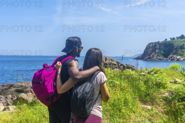 Couple savoring a stunning ocean view during a summer hike, celebrating the beauty of nature and their shared adventure together