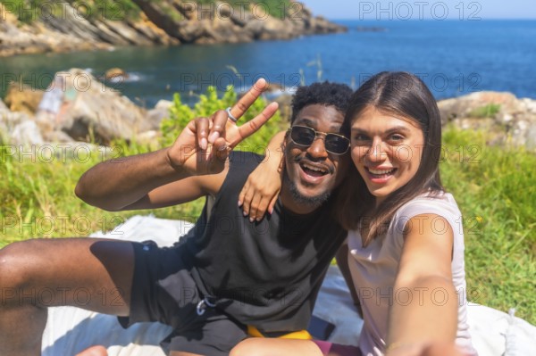 Young tourists enjoying a sunny day by the sea, sharing joyful moments while taking selfies and flashing peace signs together