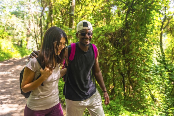 Happy couple hiking together, enjoying a scenic walk along a lush green forest trail, surrounded by vibrant trees and peaceful nature
