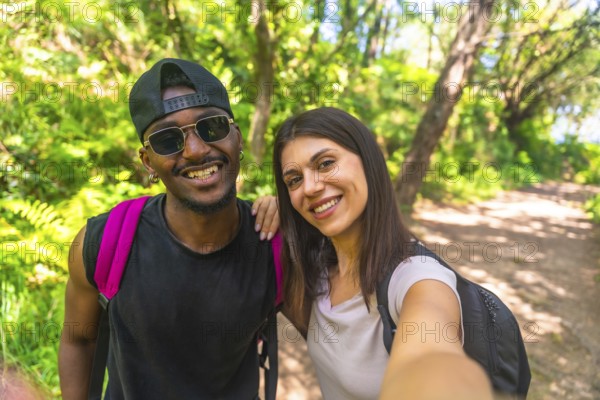 Happy couple taking selfie while hiking in a tropical forest, enjoying their outdoor adventure