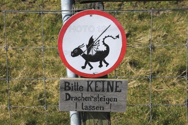 Humour, sign Please do not fly kites, on a dyke near Westerhever on the North Sea, North Frisia, Germany, sign with a fantasy kite on a line