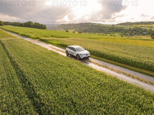 A modern car on a path through agricultural fields under a cloudy sky, Deer E- CarSharing, Renault Megane electric car, Calw, Black Forest, Germany