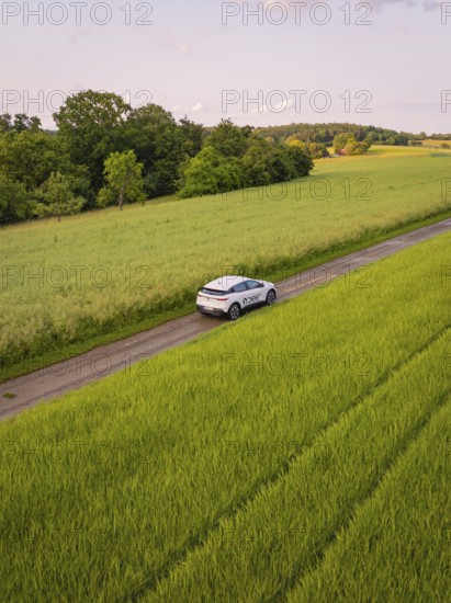 Car drives through rural route surrounded by green fields and summer landscape, Deer E- CarSharing, Renault Megane electric car, Calw, Black Forest, Germany