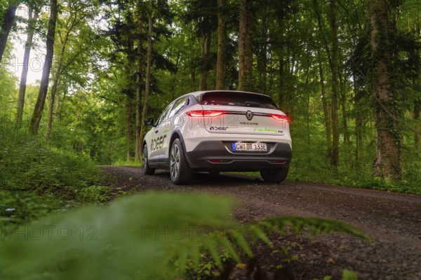 Car with glowing tail lights drives through green forest path, surrounded by nature, Deer E- CarSharing, Renault Megane electric car, Calw, Black Forest, Germany