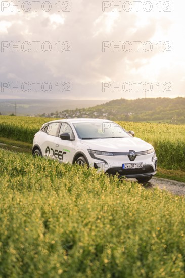 Car next to a field in a hilly landscape at sunset, Deer E- CarSharing, Renault Megane electric car, Calw, Black Forest, Germany