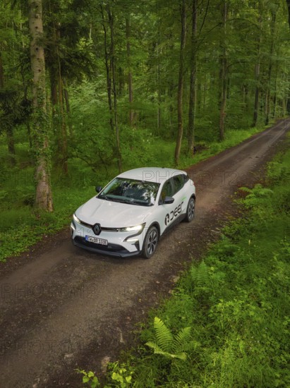 A car drives along a quiet forest path surrounded by dense green forest, Deer E- CarSharing, Renault Megane electric car, Calw, Black Forest, Germany