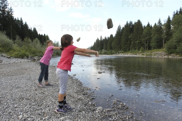 Girls, children throwing stones into a river, activity with children in nature, Allgäu, Bavaria, Germany, Allgäu, Bavaria, Germany