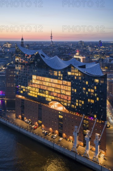 Aerial view of the Elbphilharmonie at sunset with illuminated windows and view over Hamburg and the main church St Michaelis (Michel), Hamburg, Germany