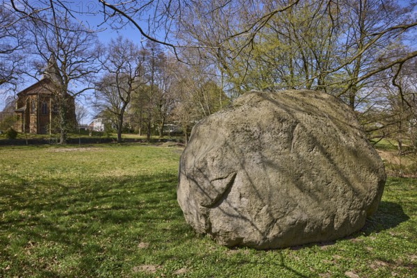 Boulder from southern Sweden, granite, Saale Ice Age, lawn, bare winter trees, blue cloudless sky, Pfarrer-Dustmann-Straße, Bad Oeynhausen, Mühlenkreis Minden-Lübbecke, North Rhine-Westphalia, Germany
