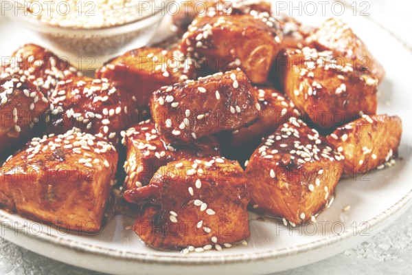 Fried pieces of salmon teriyaki with sesame seeds, top view