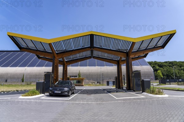 Electric charging station on the site of the former Lohberg colliery in Dinslaken, operated by Fastned, uses electricity from wind power and solar energy, fast-charging columns, with its own solar roof, in the background the 11, 500 square metre solar roof on the colliery's former coal mixing hall, North Rhine-Westphalia, Germany