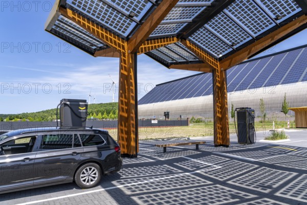 Electric charging station on the site of the former Lohberg colliery in Dinslaken, operated by Fastned, uses electricity from wind power and solar energy, fast-charging columns, with its own solar roof, in the background the 11, 500 square metre solar roof on the colliery's former coal mixing hall, wind farm on the Lohberg slagheap, North Rhine-Westphalia, Germany