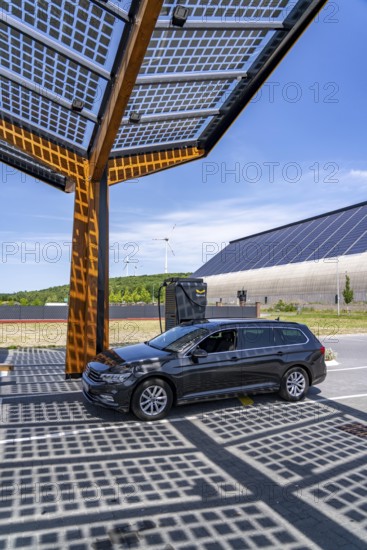Electric charging station on the site of the former Lohberg colliery in Dinslaken, operated by Fastned, uses electricity from wind power and solar energy, fast-charging columns, with its own solar roof, in the background the 11, 500 square metre solar roof on the colliery's former coal mixing hall, wind farm on the Lohberg slagheap, North Rhine-Westphalia, Germany