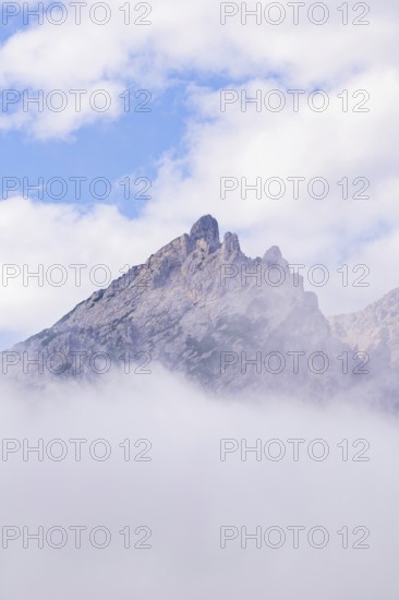 An isolated mountain peak rises through fog into the clear sky, Dolomites, South Tyrol, Dolomites, Italy