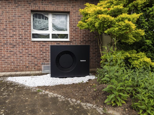 A black heat pump in a front garden in Hilden, Germany