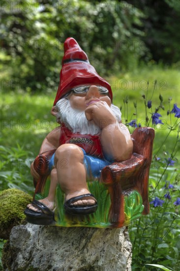 Sitting garden gnome in a garden, Bavaria, Germany