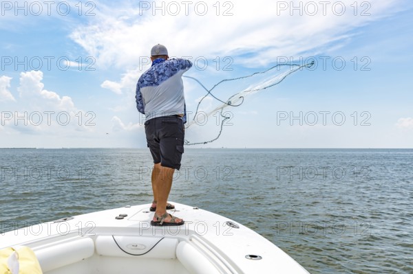 Fisherman throwing cast net to catch bait fish for offshore fishing trip in Gulf of Mexico
