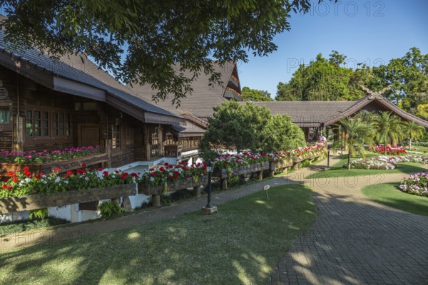 Ornate trees and lush flower gardens enhance the Lanna and Swiss architecture of the Doi Tung Royal Villa inside the Doi Tung tourist attraction in Chiang Rai, Thailand