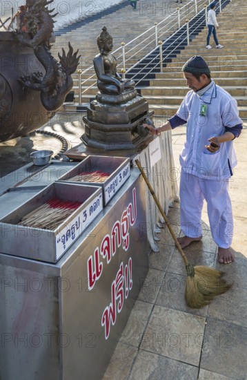 Worker cleaning Buddhist statue in fron of the Guan Yin (Goddess of Mercy) statue at Wat Huay Pla Kang Temple in Chiang Rai province of Northern Thailand