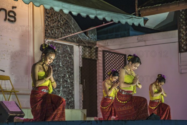 Traditional Thai dancers perform on a lighted stage at the night market in downtown Chiang Rai, Thailand