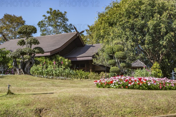 Ornate trees and lush flower gardens enhance the Lanna and Swiss architecture of the Doi Tung Royal Villa inside the Doi Tung tourist attraction in Chiang Rai, Thailand