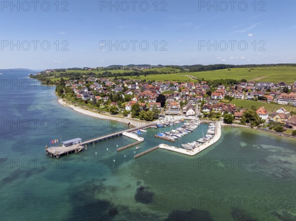 Luftbild von der Bodenseegemeinde Hagnau, Winzerdorf und beliebter Ferienort am Bodensee, dahinter Rebhänge, auf denen hauptsächlich die Weinsorten Müller Thurgau und Blauer Burgunder angebaut werden. Am Seeufer der am 23.Mai 2025 eingeweihte, neue Westhafen, Yachthafen mit der Schiffanlegestelle, Bodenseekreis, Baden-Württemberg, Deutschland