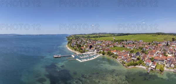 Luftbild, Panorama von der Bodenseegemeinde Hagnau, Winzerdorf und beliebter Ferienort am Bodensee, dahinter Rebhänge, auf denen hauptsächlich die Weinsorten Müller Thurgau und Blauer Burgunder angebaut werden. Am Seeufer der am 23.Mai 2025 eingeweihte, neue Westhafen, Yachthafen mit der Schiffanlegestelle, Bodenseekreis, Baden-Württemberg, Deutschland