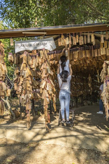 Thai women hanging their personal message plaque near the entrance to the Akha Cottage restaurant and coffee shop in Chiang Rai, Thailand