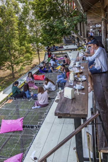 Customers eat, drink and relax on a net suspended over the hillside at the Akha Cottage restaurant and coffee shop in Chiang Rai, Thailand