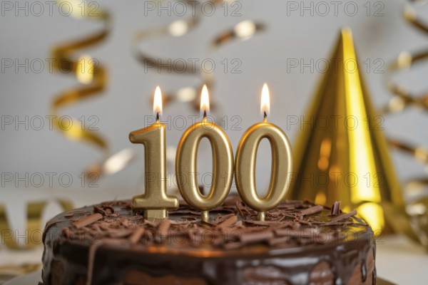 Chocolate cake with golden candles spelling 100. Celebration of longevity and reaching 100 years with festive gold decorations. Generative ai, AI generated