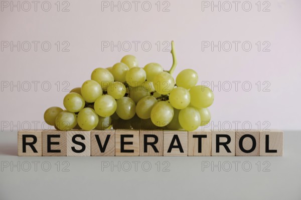 Fresh green grapes beside wooden blocks spelling Resveratrol. Clean studio image highlighting antioxidant-rich fruit. Generative ai, AI generated