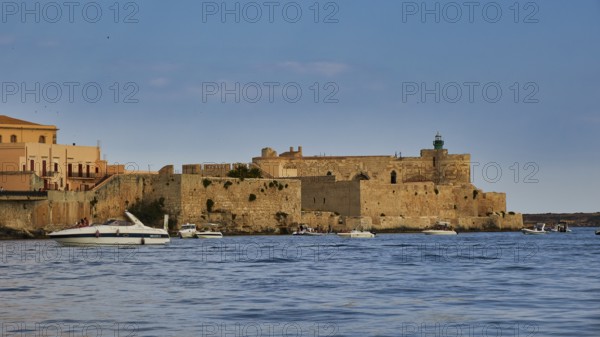 Castello Maniace, Maniace sea fortress, old defence defence tower by the sea with passing boats under a clear sky, boat trip around the island of Ortigia, Isola di Ortigia, Syracuse, Sicily, Italy