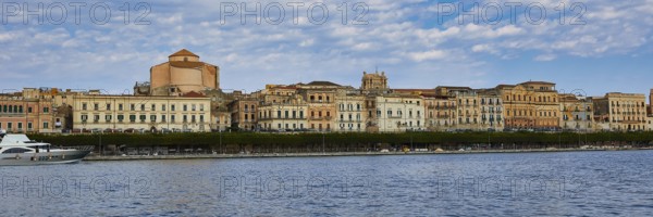 Coastal view with historic buildings against a cloudy blue sky on the promenade, boat trip around the island of Ortigia, Isola di Ortigia, Syracuse, Sicily, Italy