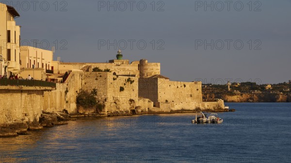 Castello Maniace, Maniace sea fortress, Mediterranean landscape with historic buildings and boat in the golden evening light, Ortigia island, Isola di Ortigia, historic old town, Syracuse, Sicily, Italy