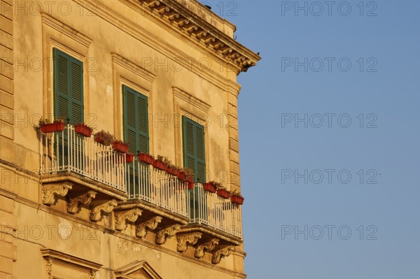 Facade of a building with balconies and green shutters in the sunlight, Ortigia Island, Isola di Ortigia, Historic Centre, Syracuse, Sicily, Italy
