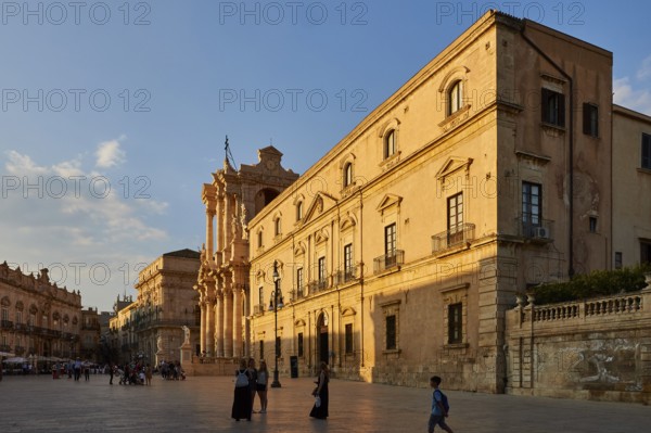 Large building with classical architecture on a sunny square with passers-by, Ortigia Island, Isola di Ortigia, Historic Centre, Syracuse, Sicily, Italy